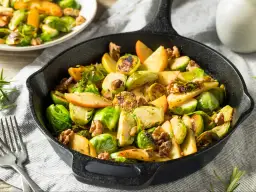 Pyszna sałatka z brukselki z jabłkami i orzechami włoskimi, podana w żeliwnej patelni.