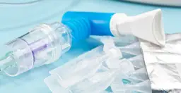 Inhalator, ampułki z lekiem do inhalacji i maseczka na niebieskim tle.