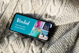 Telefon z aplikacją Vinted na tle dzianinowego swetra.