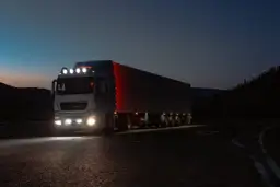 Ciężarówka z naczepą jedzie nocą po pustej drodze. Zastanawiasz się, ile zarabia kierowca tira w USA?