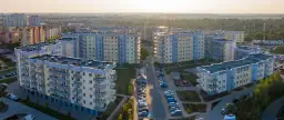 Widok z lotu ptaka na osiedle bloków mieszkalnych z balkonami i parkingami.