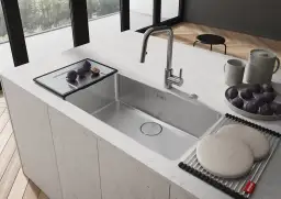 Nowoczesny zlew kuchenny ze stali nierdzewnej, z baterią i tacą z figami.