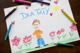 Dziecko narysowało laurkę dla taty z uśmiechniętą buzią, słońcem i kwiatami.