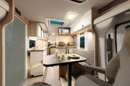 Wnętrze kampera: stół z napojami, aneks kuchenny, kanapa i telewizor.