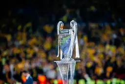Trofeum Ligi Mistrzów na tle rozmazanej publiczności. Wartość awansu do Ligi Mistrzów jest ogromna.
