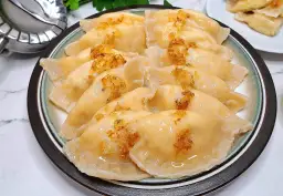 Talerz pełen pysznych pierogów ruskich, polanych tłuszczem i posypanych skwarkami. Idealne, by pokazać, jak zrobić pierogi ruskie.