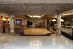 Eleganckie lobby hotelowe z fortepianem, recepcją i dwoma pracownikami.