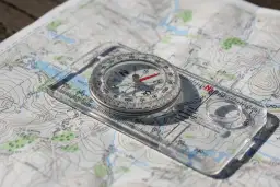 Kompas na mapie topograficznej, gotowy do nawigacji.