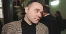 Mężczyzna w tweedowej marynarce, jak zostałem gangsterem o kim, w tle prawnik w todze.
