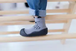 Szare skarpeto-buty z misiem, idealne dla dziecka z wysokim podbiciem, zapewniające komfort i bezpieczeństwo podczas zabawy.