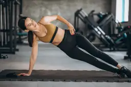 Kobieta wykonuje boczną deskę, ćwiczenie idealne na trening core dla początkujących.