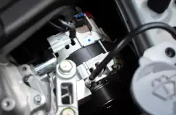 Zbliżenie na alternator samochodowy z widocznym sprzęgiełkiem i elementami mocowania.