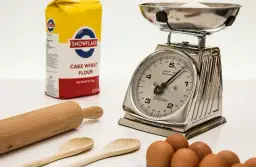 Mąka, waga kuchenna, wałek i jajka na białym tle.