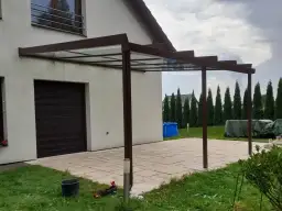 Nowoczesne zadaszenie tarasu z przezroczystym dachem, przyścienne, z brązową konstrukcją.