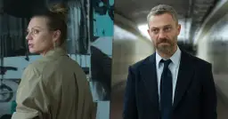 Kobieta z artystycznym nieładem na głowie i mężczyzna w garniturze, bohaterowie serialu "W głębi lasu", patrzą w różne strony, jakby coś ich niepokoiło.