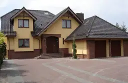 Dom z żółtą elewacją i brązowym dachem. Zastanawiasz się, ile waży dachówka? Ten dach wygląda solidnie.