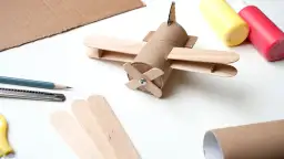 Samolot z rolki po papierze toaletowym i patyczków, obok materiały do tworzenia.