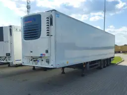 Biała naczepa chłodnia Schmitz Cargobull z niebieskim logo, zaparkowana na zewnątrz.