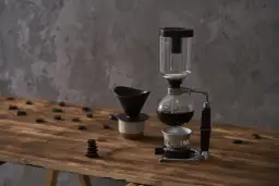 Kawiarka syfonowa i dripper na drewnianym blacie. Dowiedz się, jak długo parzyć kawę sypaną, by uzyskać idealny smak.