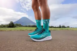 Turkusowe buty na maraton, gotowe na podbój szlaków. W tle malowniczy krajobraz z górą.