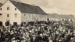 Tłum ludzi na targu w Biłgoraju, jakby żywcem wyjęty z legendy o tym mieście. W tle budynki i stragany.