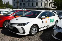Białe i czerwone samochody z logo Bolt, gotowe do jazdy. Dowiedz się, jak zostać kierowcą Bolt i zacznij zarabiać.