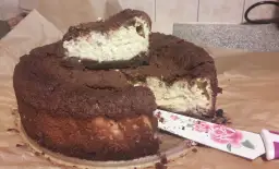 Pyszny sernik królewski bezglutenowy z czekoladową kruszonką i kremowym nadzieniem. Pokrojony kawałek czeka na spróbowanie.