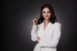 Elegancka kobieta w białej marynarce, zastanawiająca się, ile kosztuje portret u fotografa.