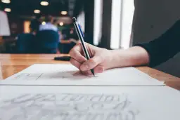 Dłoń pisze na papierze, zastanawiając się, czy odpowiedź na pozew doręcza się pełnomocnikowi.