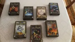 Pudełka z rozszerzeniami gry Talisman Magia i Miecz ułożone na obrusie.