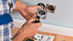 Elektryk montuje mechanizm gniazdka, pokazując jak podłączyć włącznik pojedynczy. Widać śrubokręt i przewody.