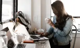 Kobieta pracuje przy laptopie, pijąc kawę. To idealne miejsce do rozwijania swoich freelancer zarobki.