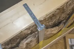 Metalowy wspornik mocowany do krokwi, z widocznymi wkrętami. Idealny do montażu wieszaków grzybkowych w izolacji poddasza.