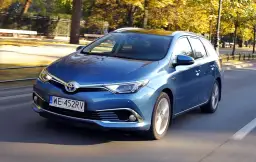 Niebieska Toyota Auris Hybrid kombi w ruchu ulicznym, jesienią.