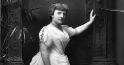 Frances Hodgson Burnett, autorka książki "Tajemniczy ogród", na czarno-białym zdjęciu pozuje w eleganckiej sukni i naszyjniku.