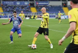 Piłkarze walczą o piłkę na boisku, decydując, kto awansuje do ekstraklasy.