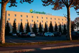 Façade de l'hôtel Campanile Guéret avec parking et arbres.
