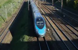 Błękitny pociąg Pendolino EIP mknie po torach.