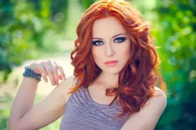 Une femme aux cheveux roux et au maquillage smoky eyes parfait, idéal pour un tuto smoky eyes débutant.