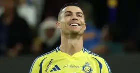 Uśmiechnięty Cristiano Ronaldo w żółtej koszulce Al Nassr. To właśnie w tym klubie gra Ronaldo.