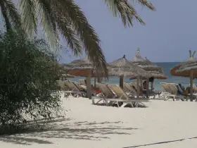 Plaża na Djerbie z leżakami i parasolami. Ludzie odpoczywają, co sugeruje, że na Djerbie jest bezpiecznie.