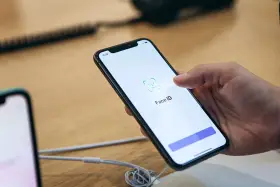 Dłoń trzyma smartfon, na ekranie którego wyświetla się komunikat "Face ID". Wygląda na to, że Face ID nie działa.