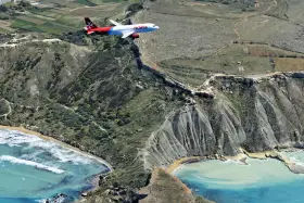 Samolot linii Malta Air przelatuje nad malowniczym wybrzeżem. Widok z lotu ptaka na maltańskie lotniska i krajobraz.