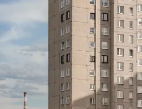 Szare bloki mieszkalne, każde mieszkanie od miasta z oknami wychodzącymi na niebo. W oddali widać komin.