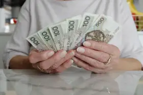 Dłonie trzymające polskie banknoty 100 i 500 zł. Numerologia 8 z dnia urodzenia może symbolizować stabilność finansową.