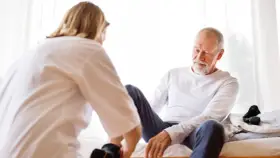 Pflegekraft hilft älterem Mann beim Aufstehen. Dies sind Beispiele für was sind pflegesachleistungen, die im häuslichen Umfeld erbracht werden.