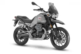 Srebrny motocykl Moto Guzzi V85 TT z czarnym siedzeniem i przyciemnianą szybą, gotowy na przygodę.