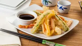 Crujiente tempura de verduras, con zanahoria, calabacín y pimiento, servida con salsa de soja.