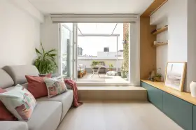 Ideas para decorar un salón rectangular: sofá gris, cojines coloridos, plantas y acceso a terraza.