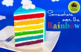 Ein Stück regenbogen kuchen mit bunten Schichten und Wolken-Deko.